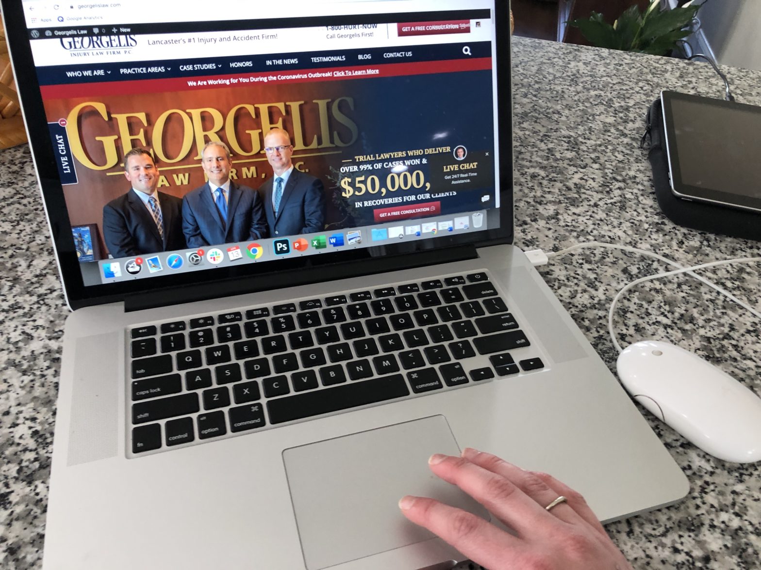A laptop in a work from home setup shows the Georgelis Injury Law website