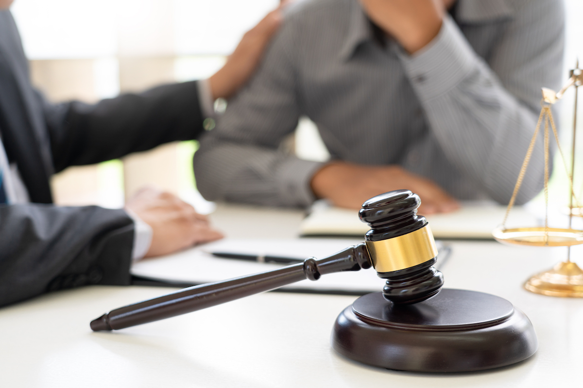 Injury attorney consults with a client, a gavel on the table