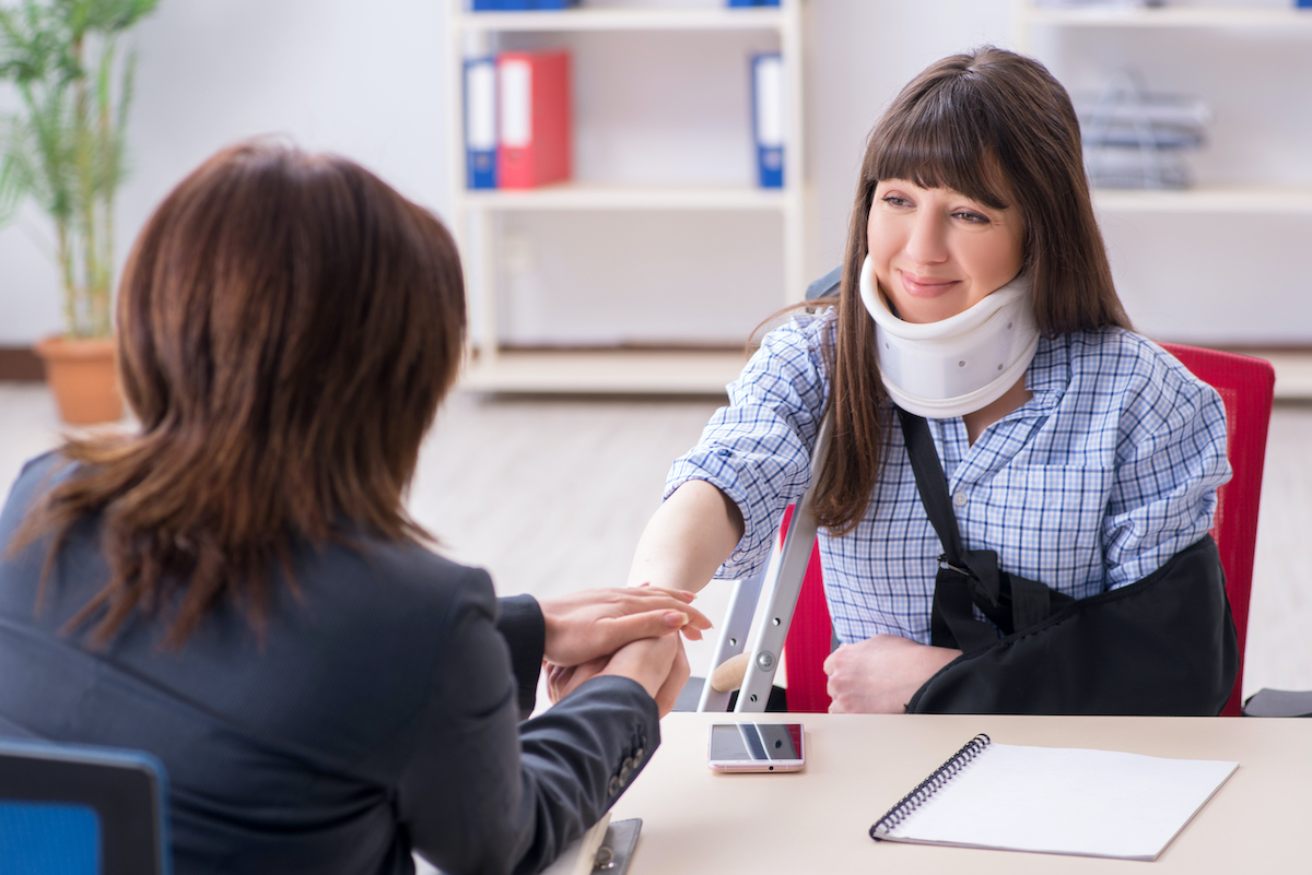 A woman with a neck brace talks with her injury lawyer