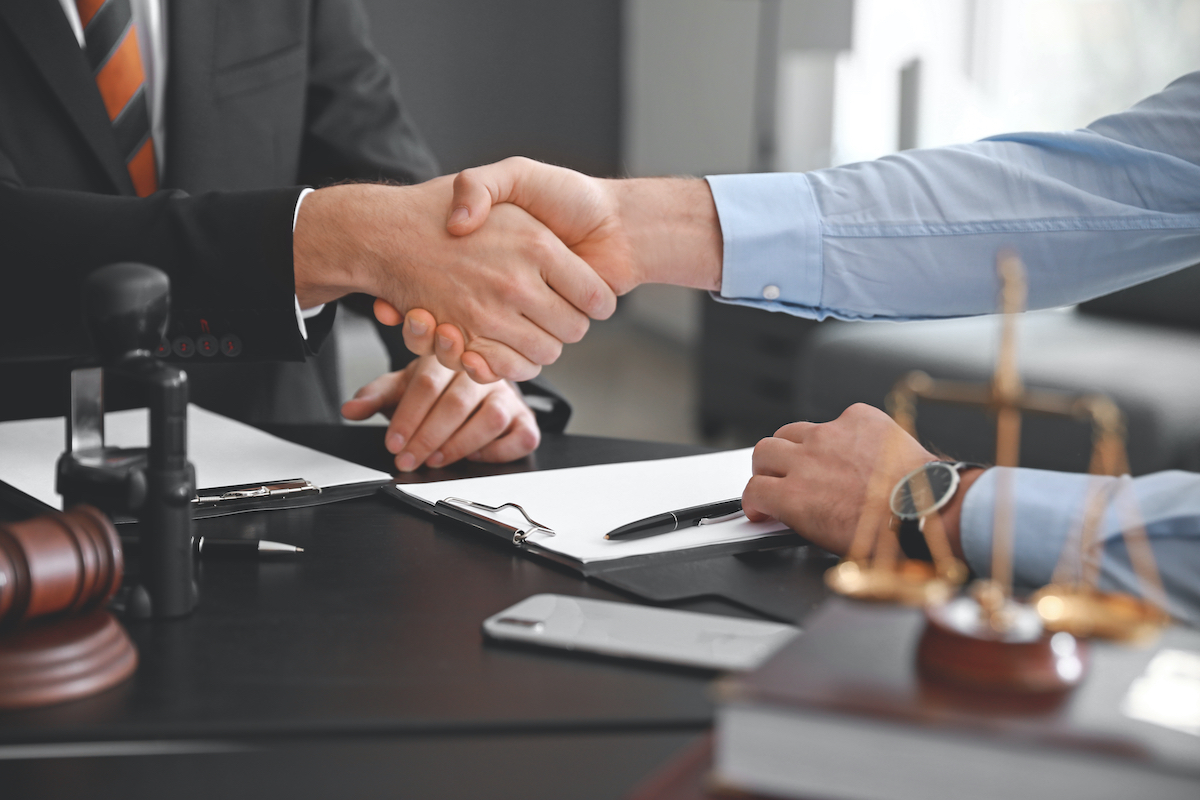A lawyer and client shake hands after a successful car accident settlement.